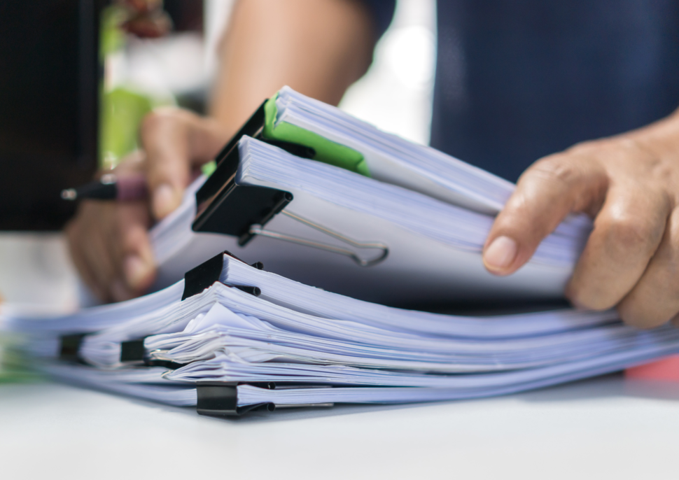 A person lifts papers from a stack of documents