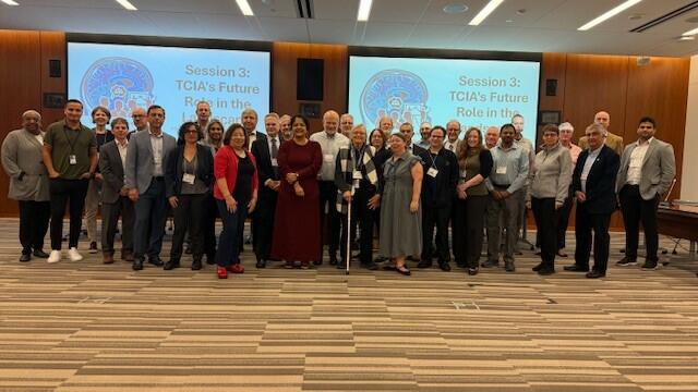 Group photo of CIP and TCIA team in front of two monitors that was taken at the TCIA Strategy Workshop in September 2025