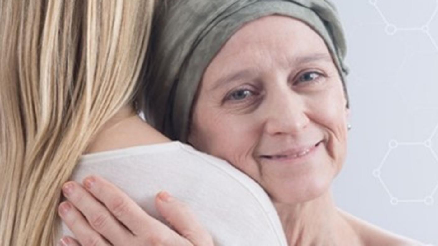 A caregiver is embracing a cancer patient who is wearing a headscarf.