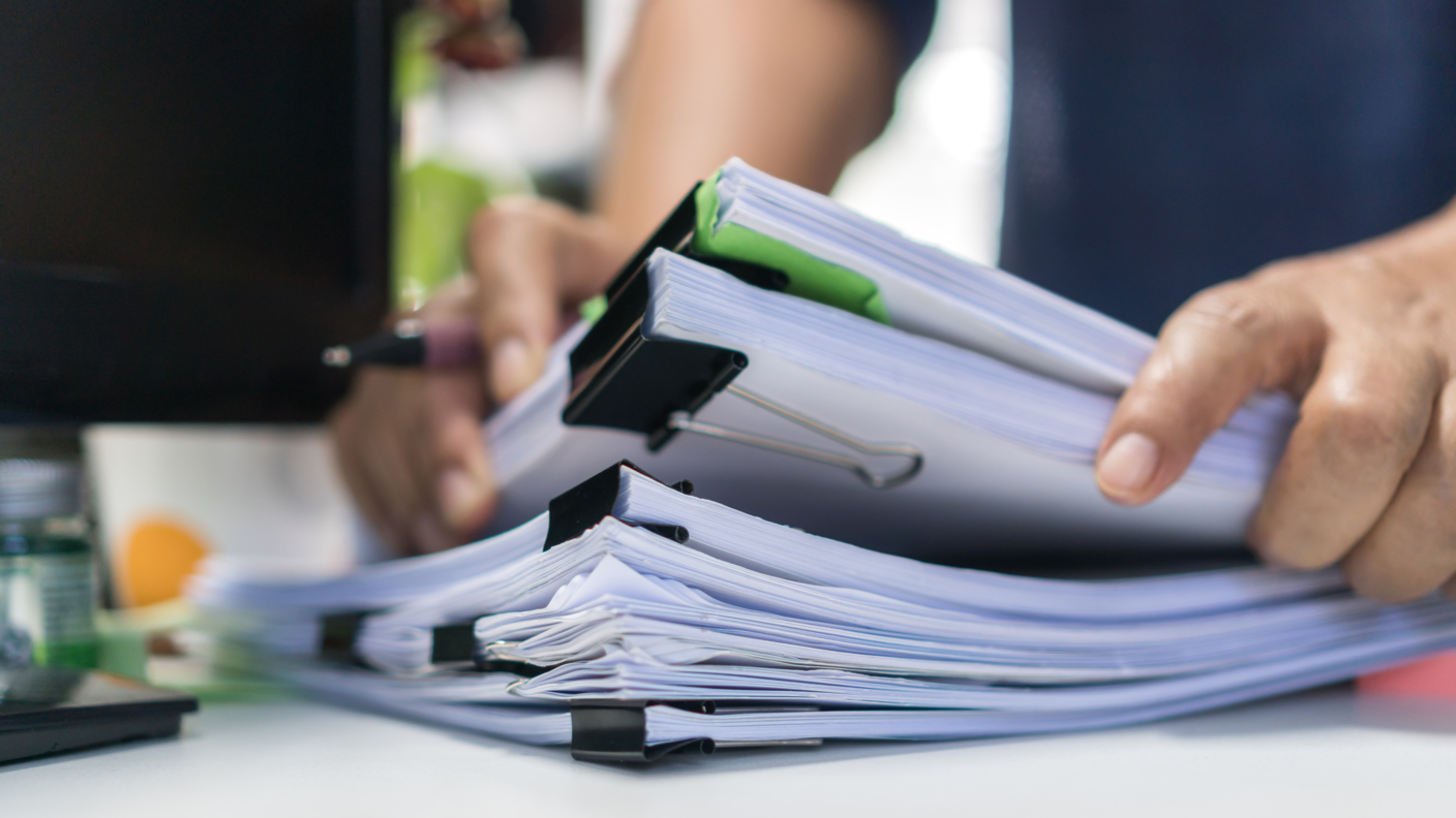 A person lifts papers from a stack of documents