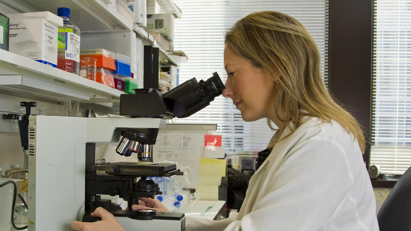A female scientist sitting at a microscope