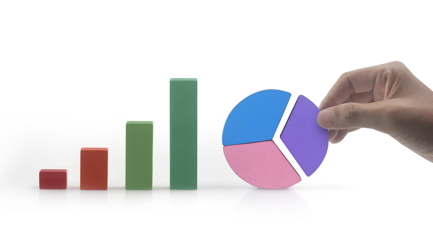 A hand holding up a pie chart next to a bar chart