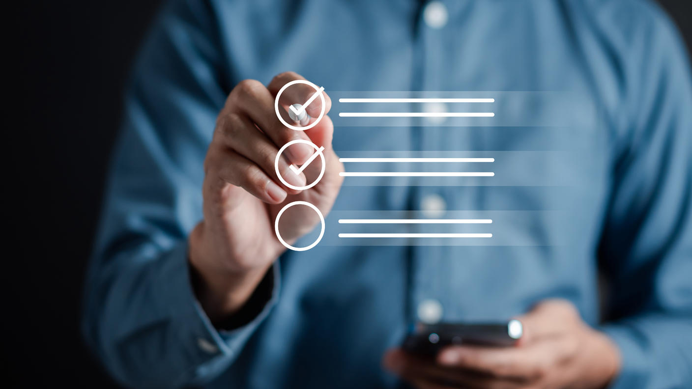 A man is checking off an item from a checklist from a screen in front of him